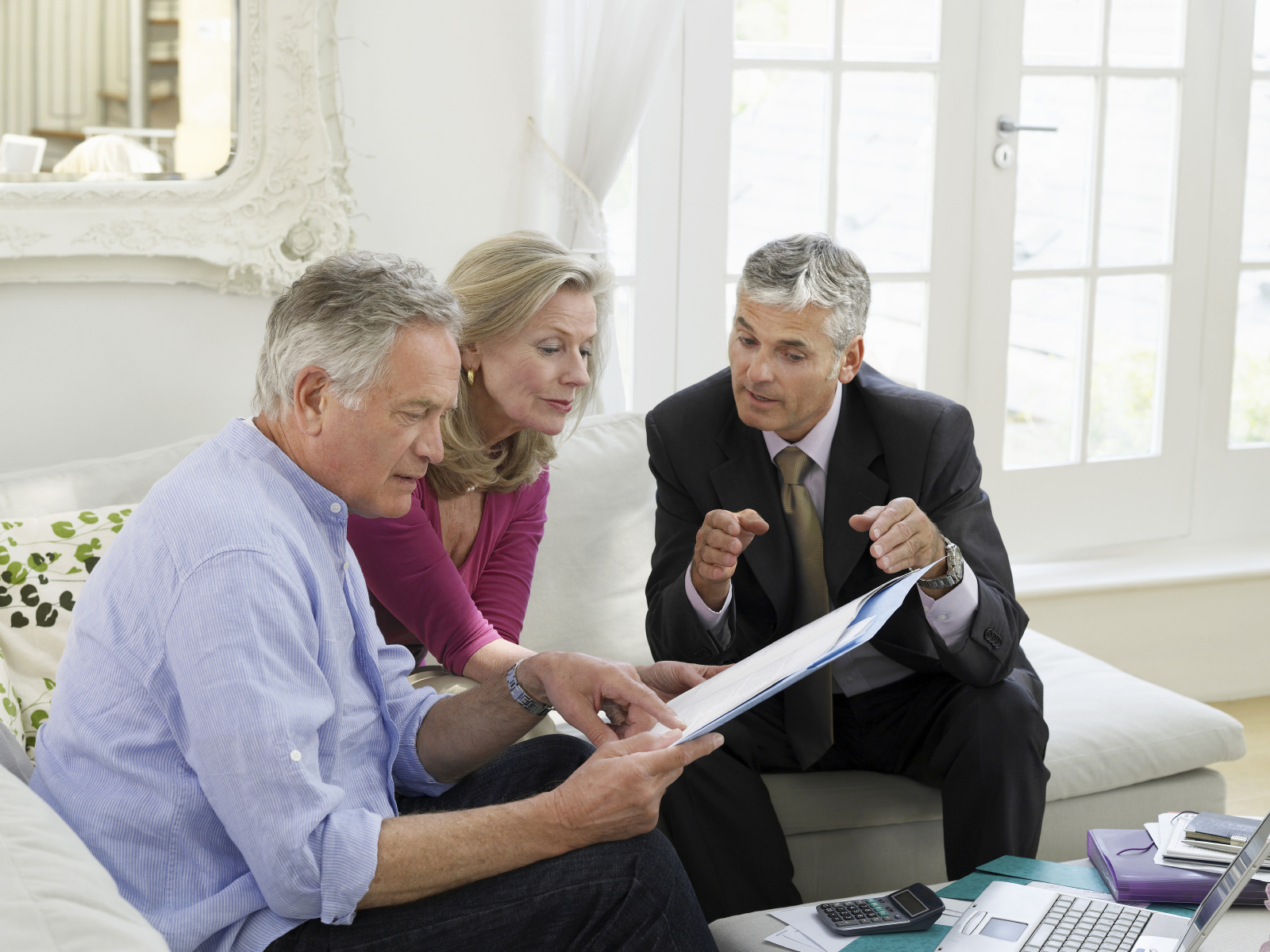 Couple With Financial Advisor At Sofa