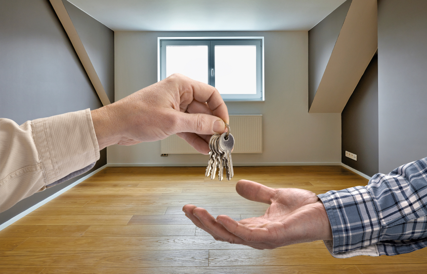 Realtor giving house key to buyer in empty room